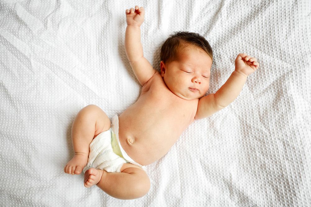 newborn baby stretching on bed