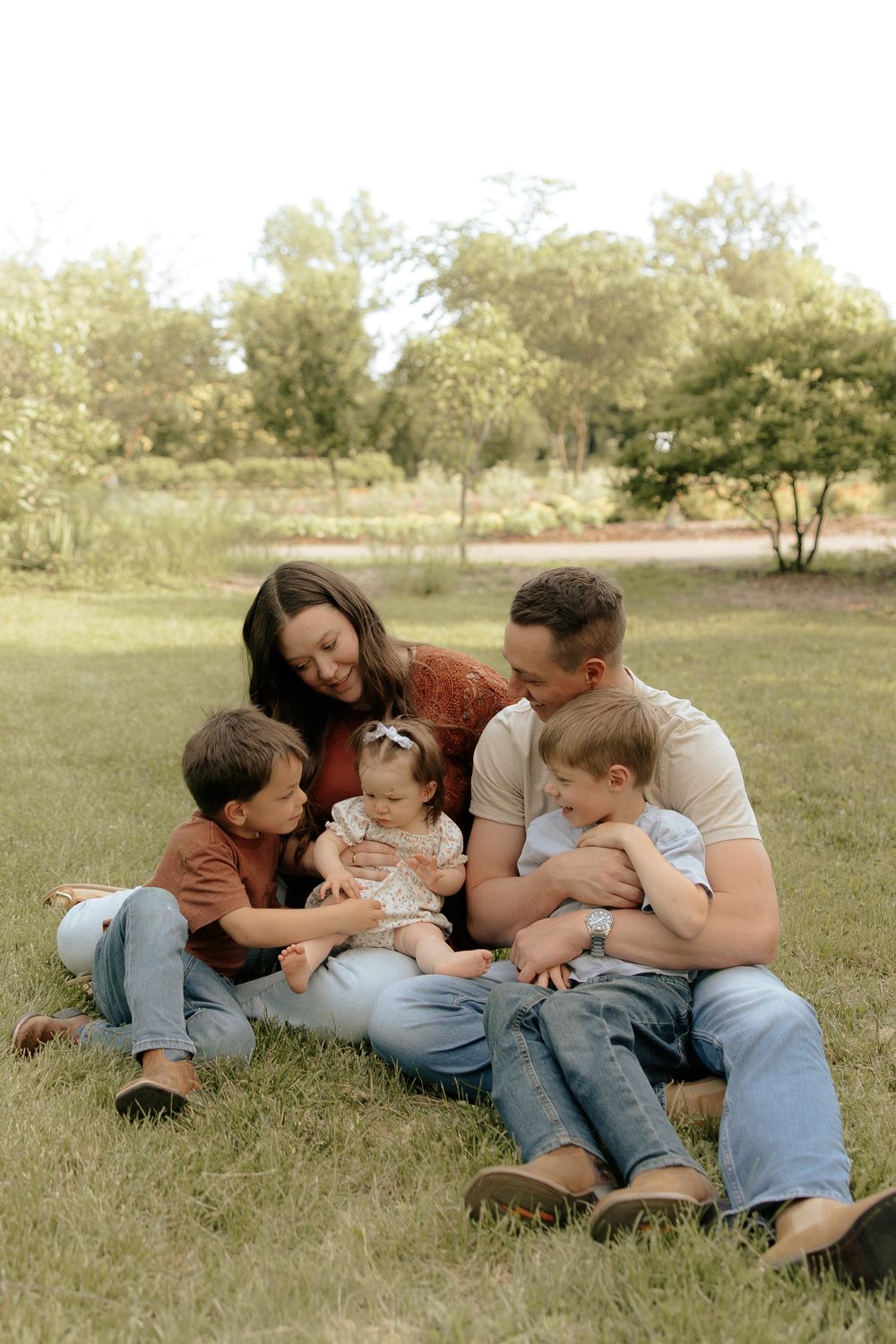 Family relaxing together on grassy field during outdoor photo session.