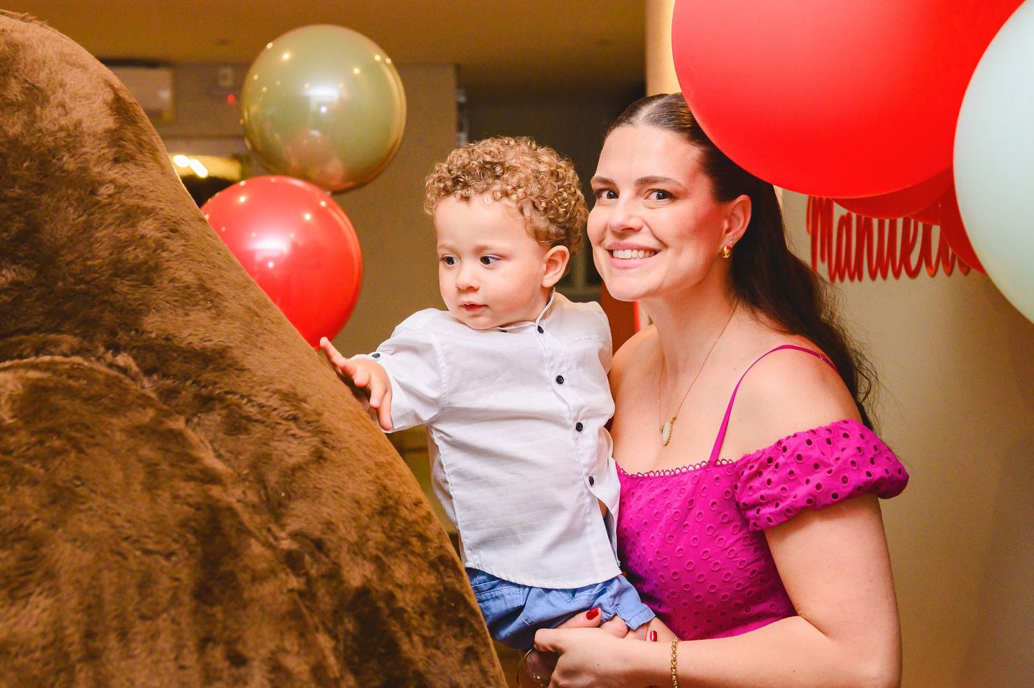 Colorful party balloons decorate a celebration with brown, red and white decorations in a festive setting.