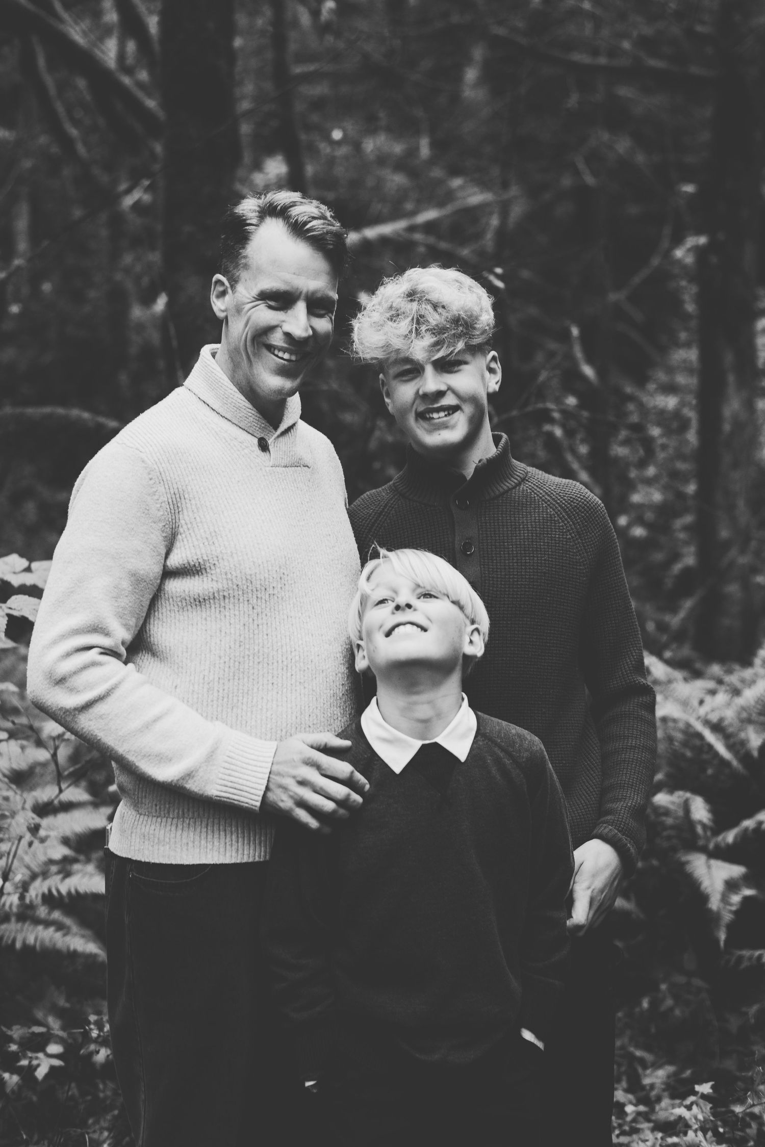 Father poses in black and white with two sons while taking family photos in goldstream provincial park.