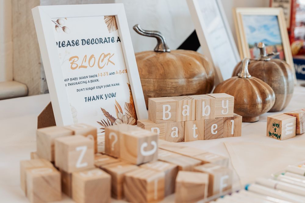 Baby shower decor with wooden blocks, pumpkins and invitation card in neutral tones.