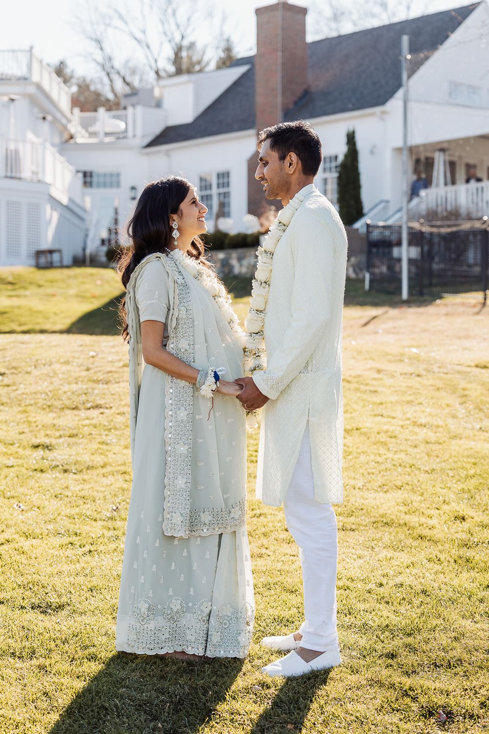 Traditional ceremony photo on sunny lawn with white house in background.