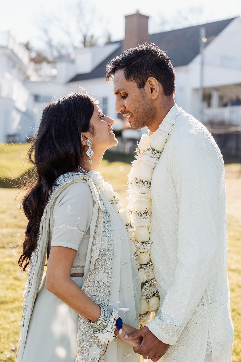 Intimate moment captured outdoors with white house visible in background.