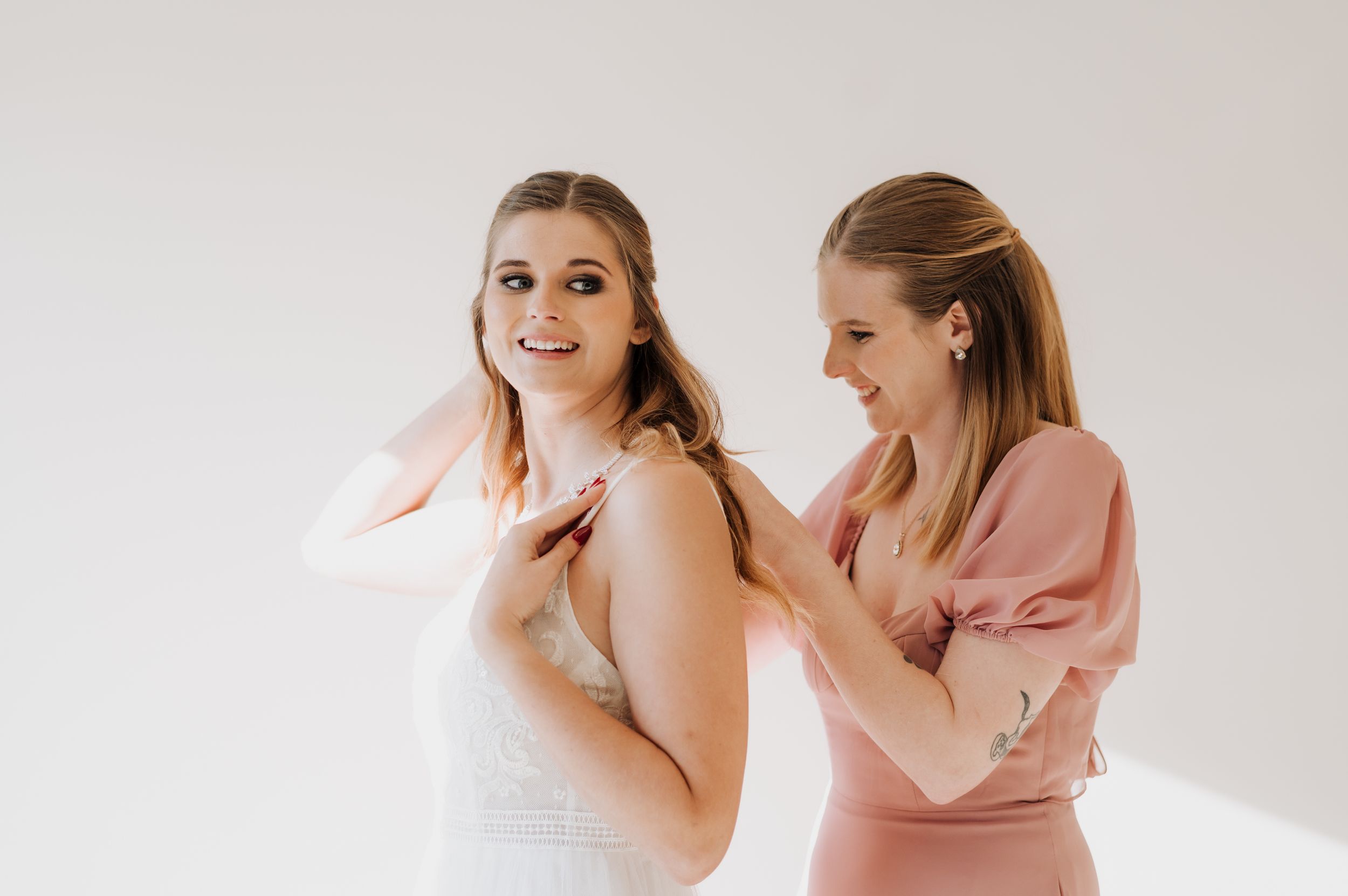 Bride getting dressed with help in morning preparations.