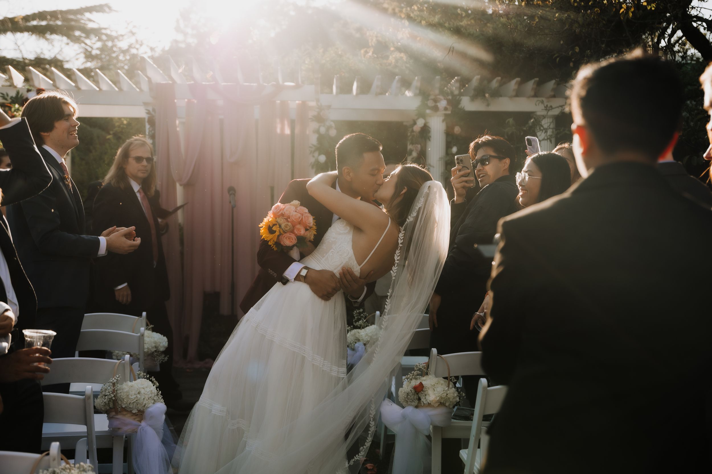 Emotional ceremony moment under outdoor gazebo with guests watching.