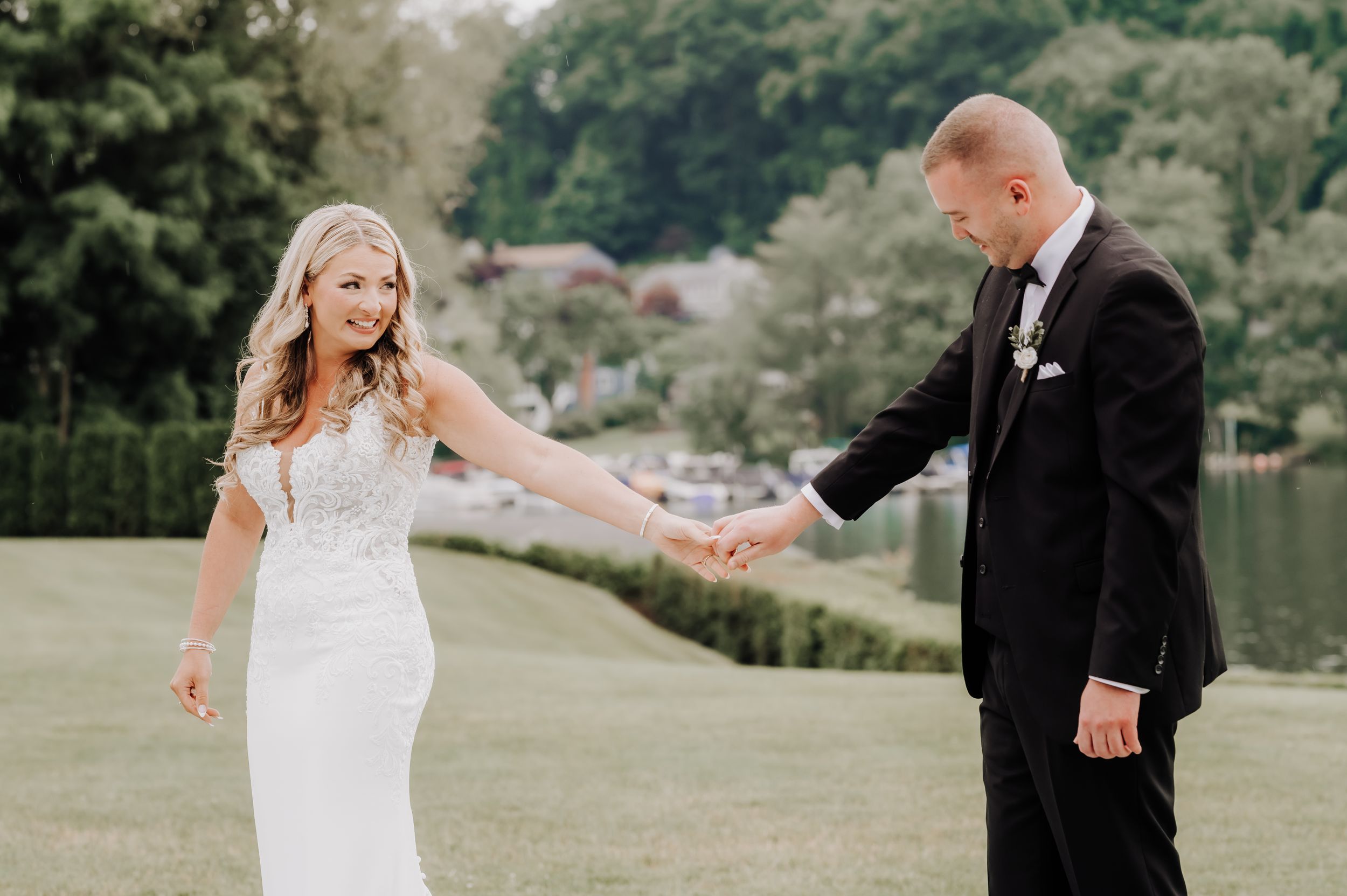 A delightful candid moment between newlyweds on a grassy lawn near a lake. Candlewood Inn, CT.