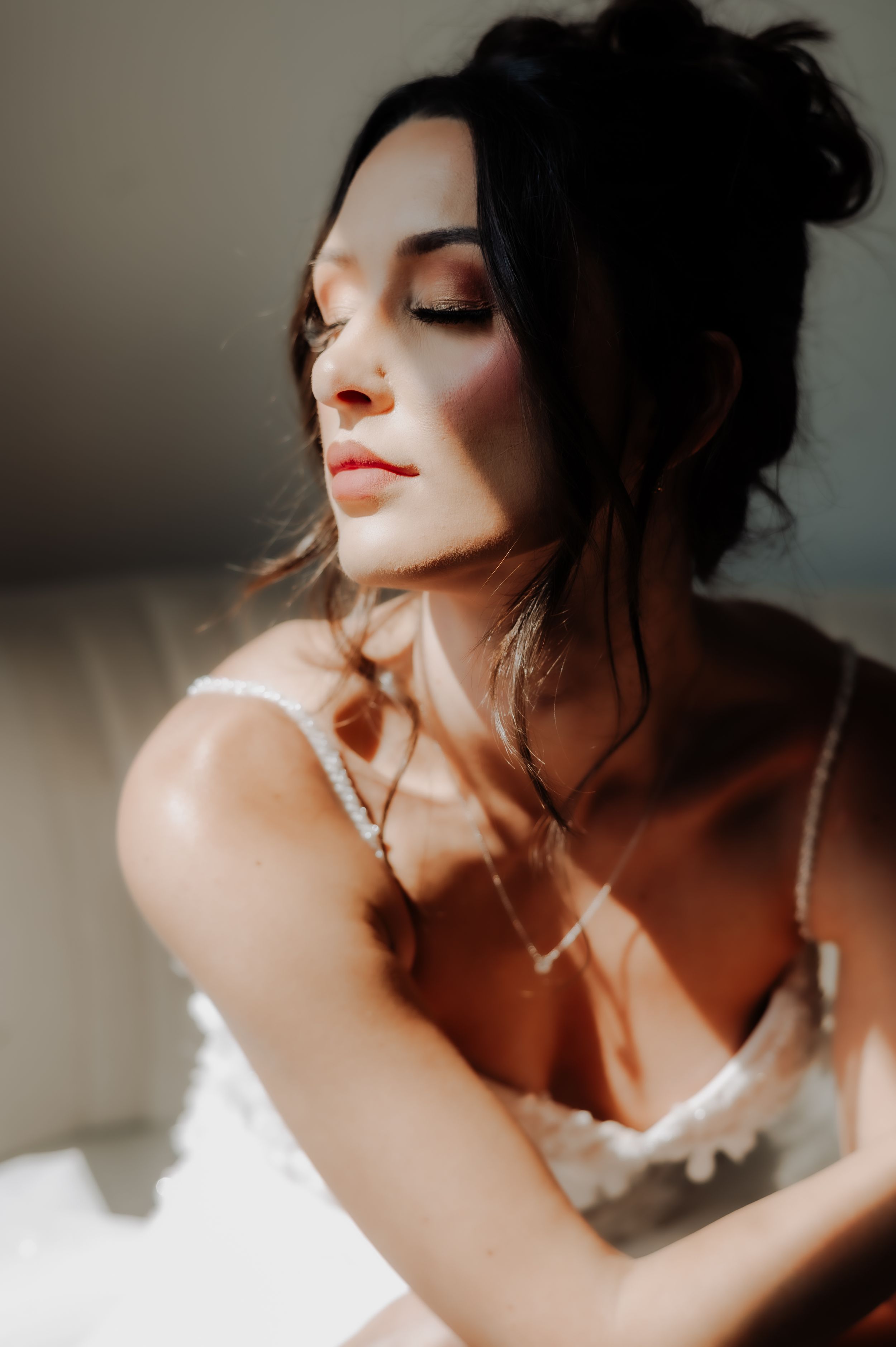 Intimate bridal portrait with sunlit skin and delicate lace dress straps.