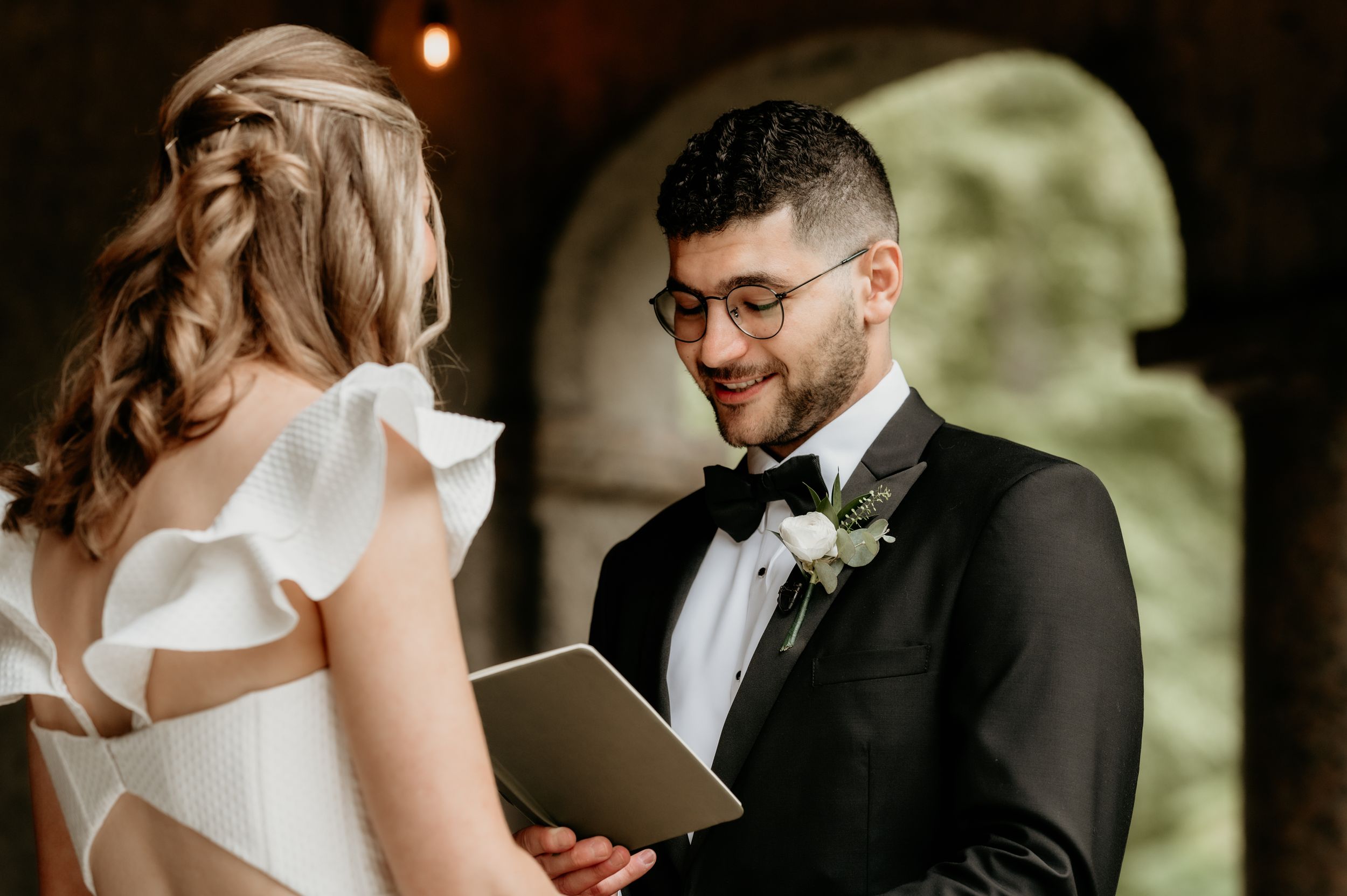 A couple shares a tender moment during their wedding ceremony while reading vows.