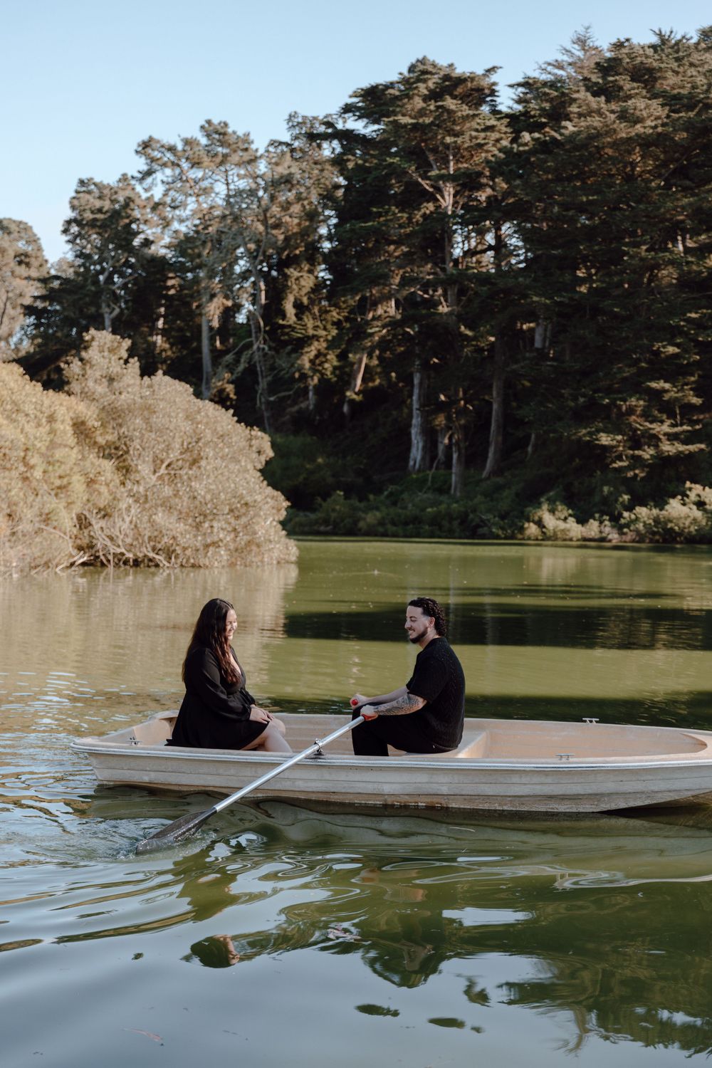 Romantic boat ride on a serene lake surrounded by tall trees.