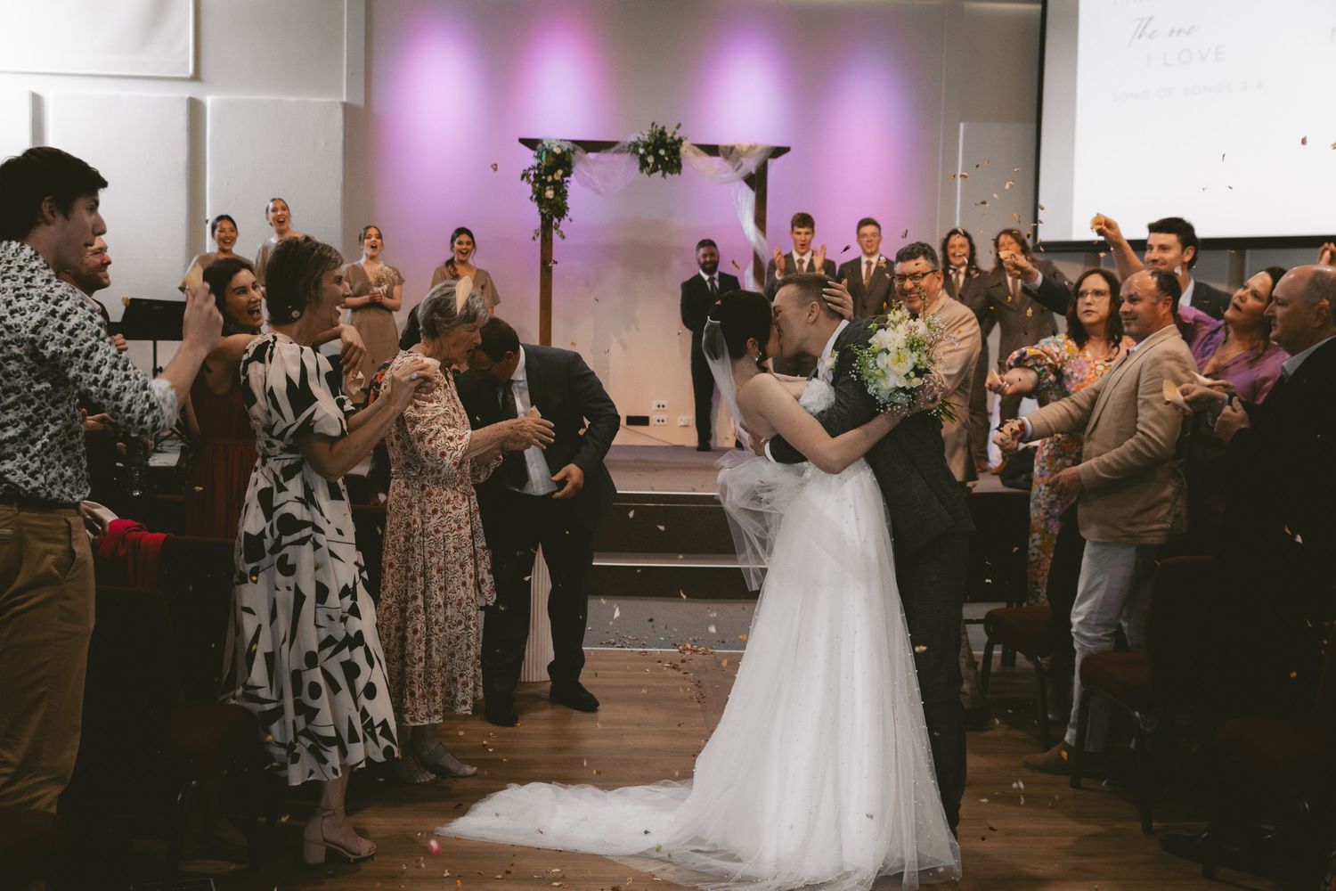 Wedding reception dancing captured in venue with purple ambient lighting.