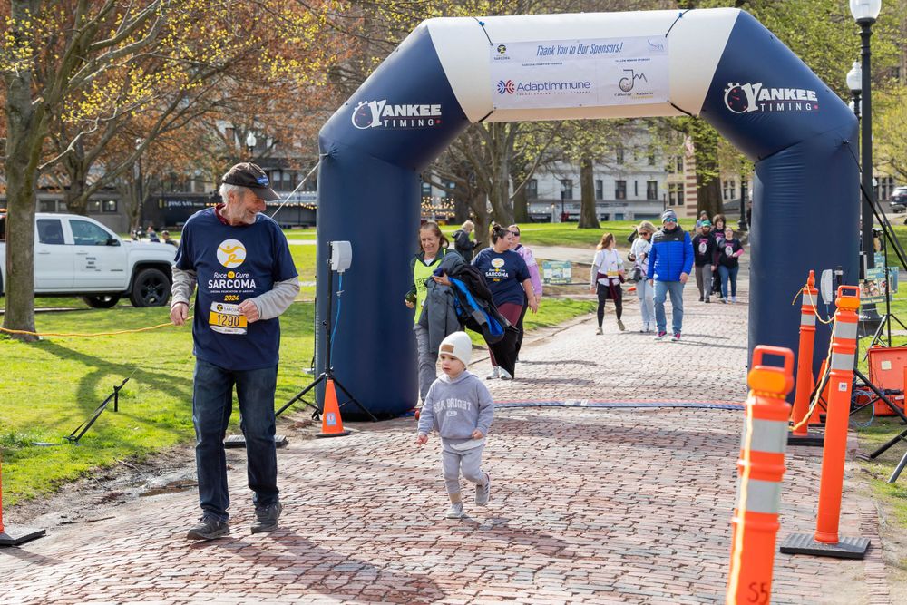 Participants crossing under a blue Yankee Fitness branded arch during a community running event.