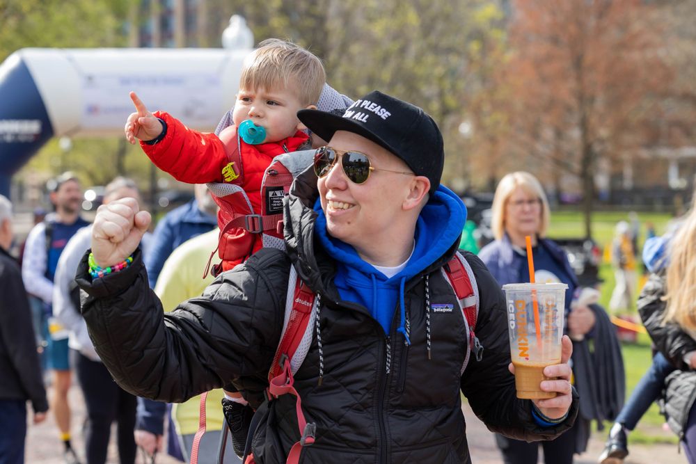 A family enjoying a race event with a blue branded arch in the background.
