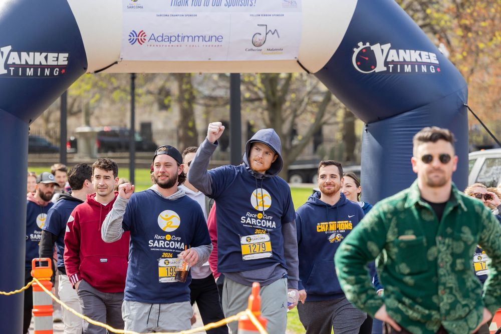 Race participants celebrating under a Yankee Fitness branded arch during an outdoor event.