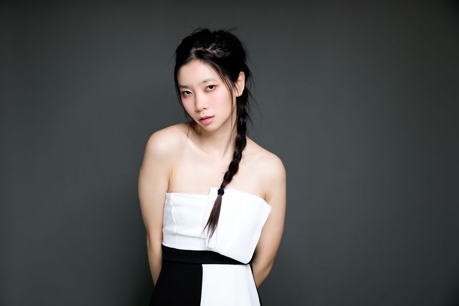 Minimalist portrait in black and white strapless dress against dark background.