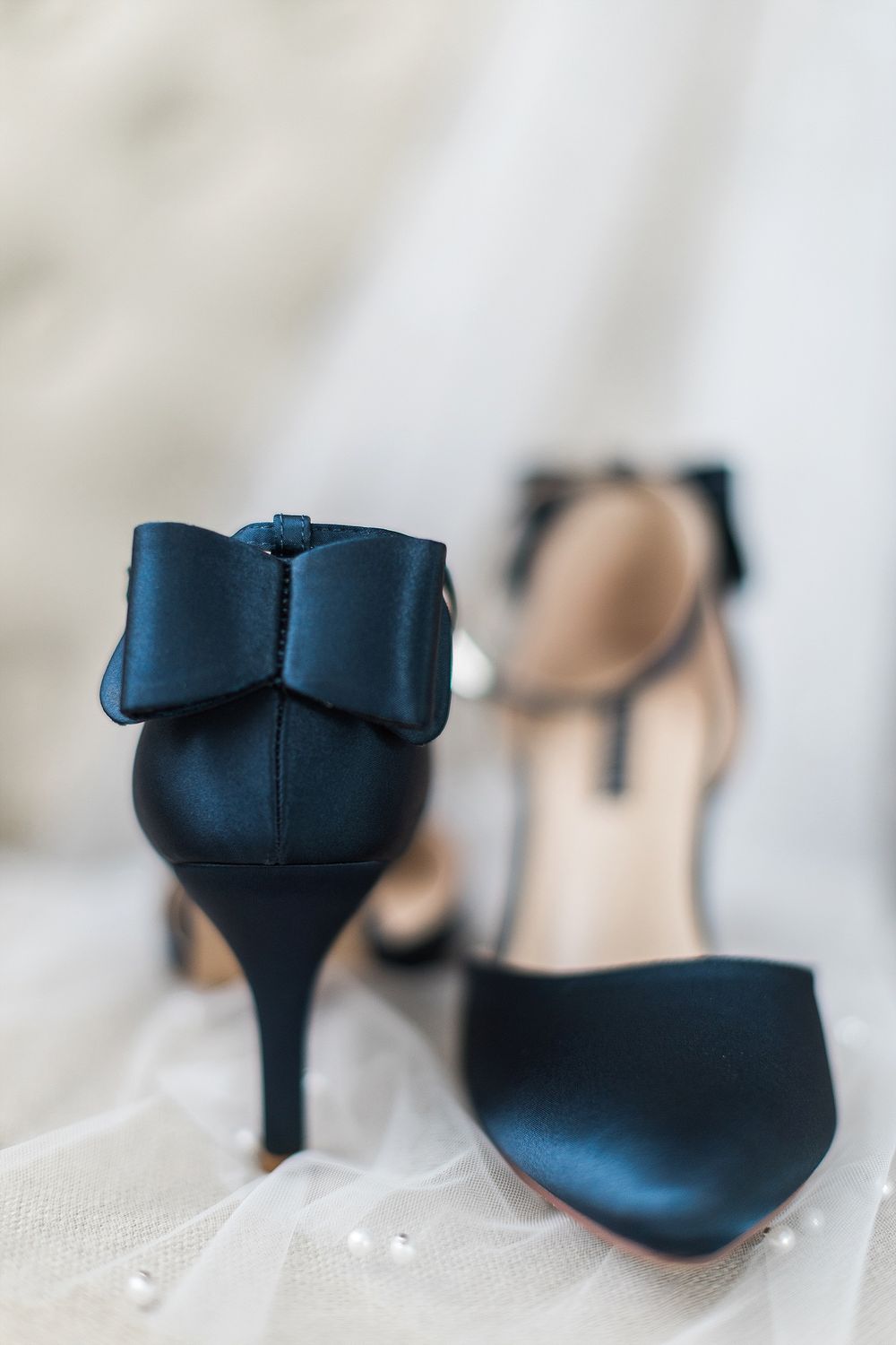 Navy blue wedding shoes with bow detail photographed on white tulle.
