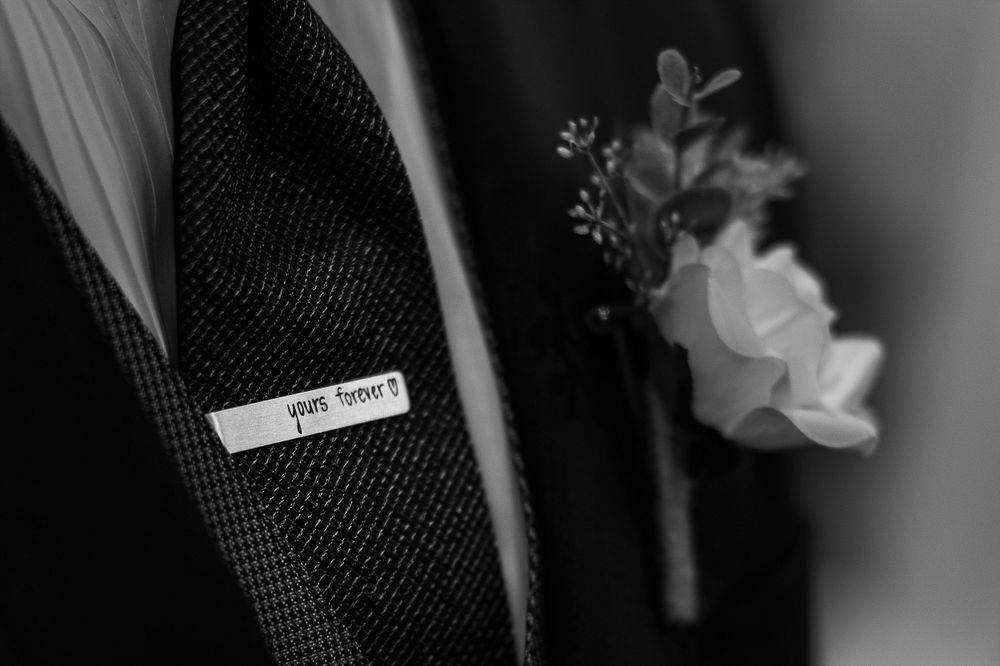 Close-up black and white detail of a boutonniere and name tag on a formal suit jacket.