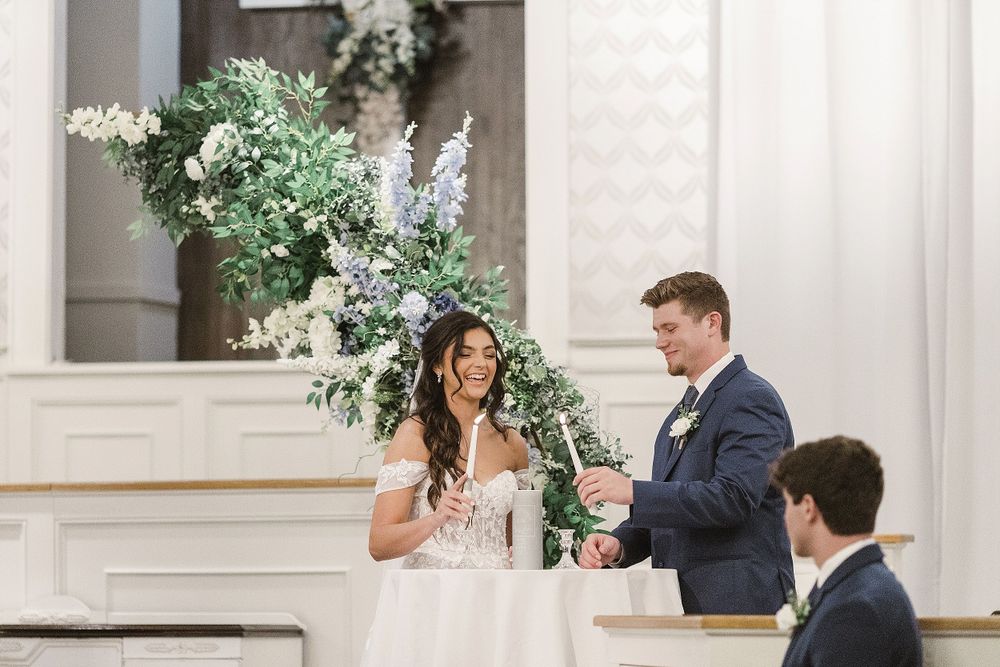 Couple exchanges vows at altar decorated with lush greenery and white flowers.