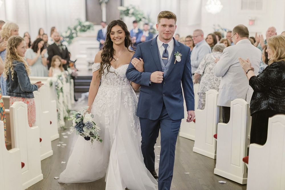 Newlyweds walk down church aisle while guests celebrate their joyous exit.