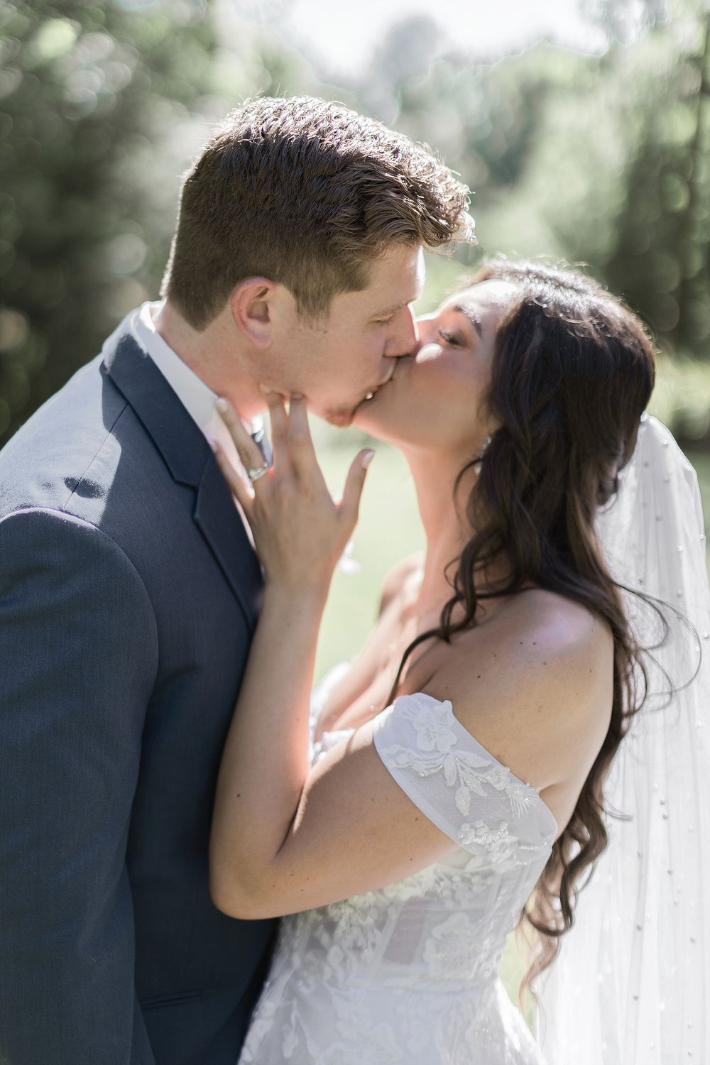 Intimate sunlit wedding portrait capturing tender moment between newlyweds.