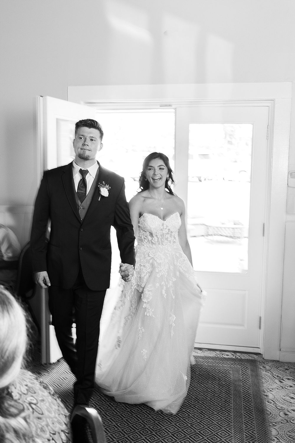 Black and white wedding entrance photo of couple making grand reception entrance.