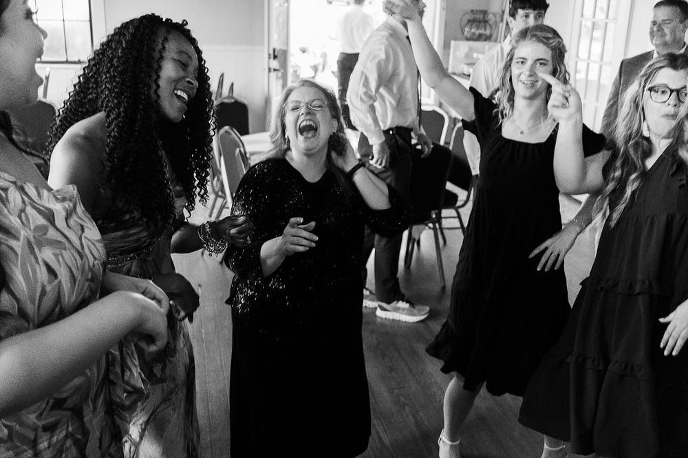 Wedding guests dancing and laughing together at a lively reception celebration.