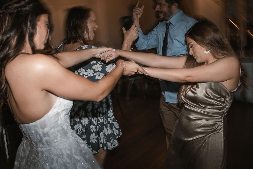 Wedding guests hold hands in a circle while dancing at the reception.