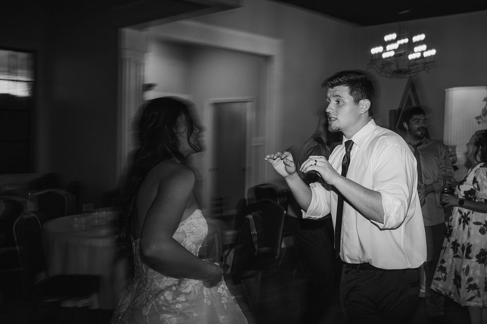 Black and white photo of guests dancing and enjoying themselves at a wedding reception.
