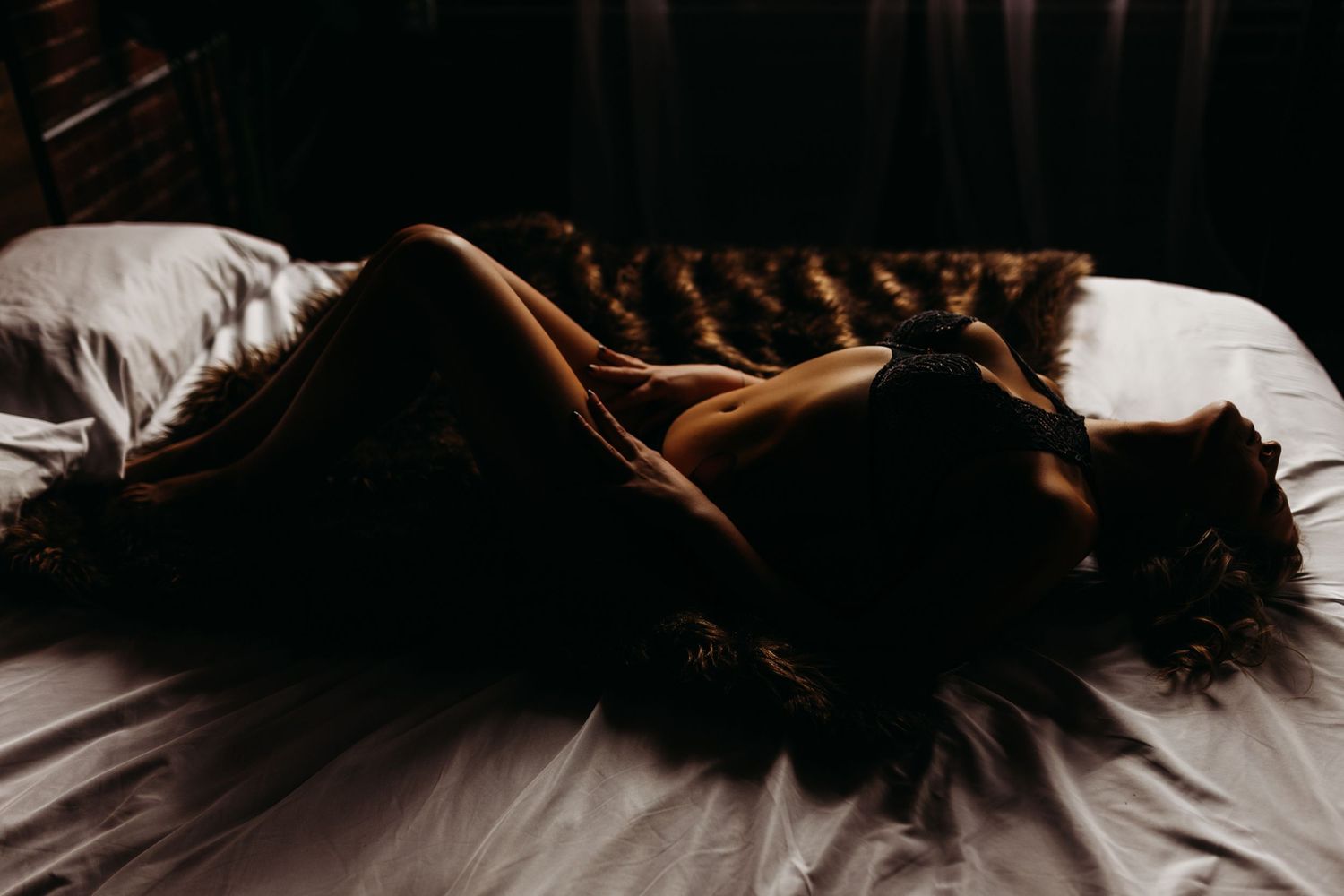Artistic silhouette photograph with dramatic shadows on white bedding.