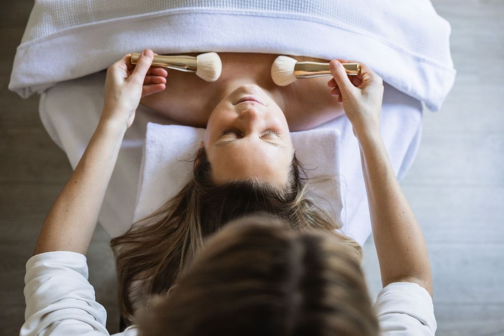 Person lying on their back on massage table with white towel during spa treatment with crystal healing stones.