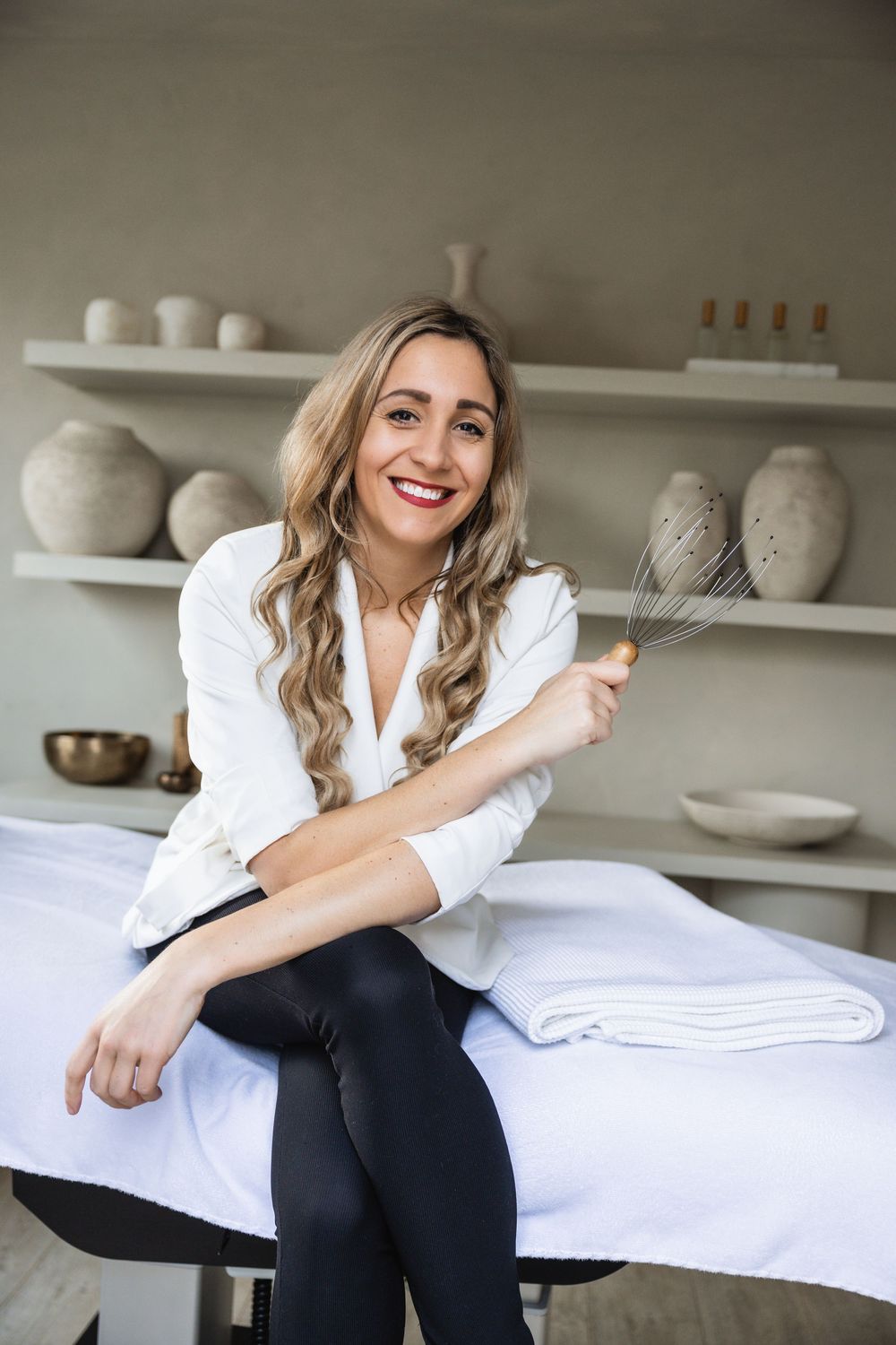 Casual portrait taken in a rustic kitchen with white pottery displayed on shelves in the background.