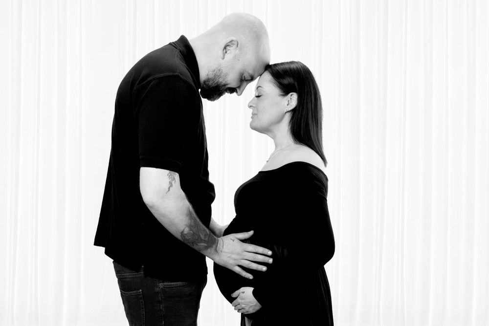 Intimate black and white portrait of expecting couple sharing a tender moment.