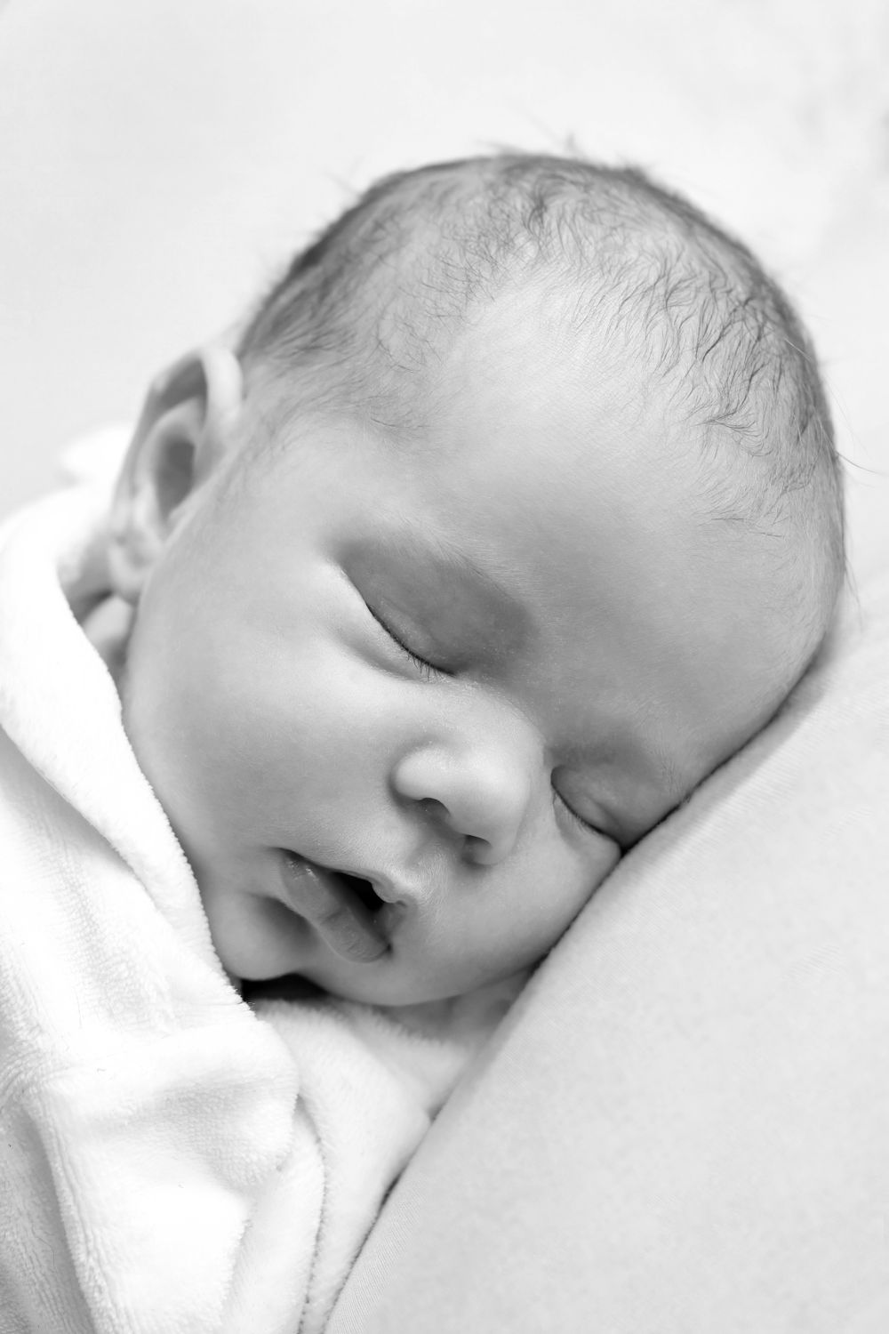 Peaceful black and white portrait of sleeping newborn against white background.