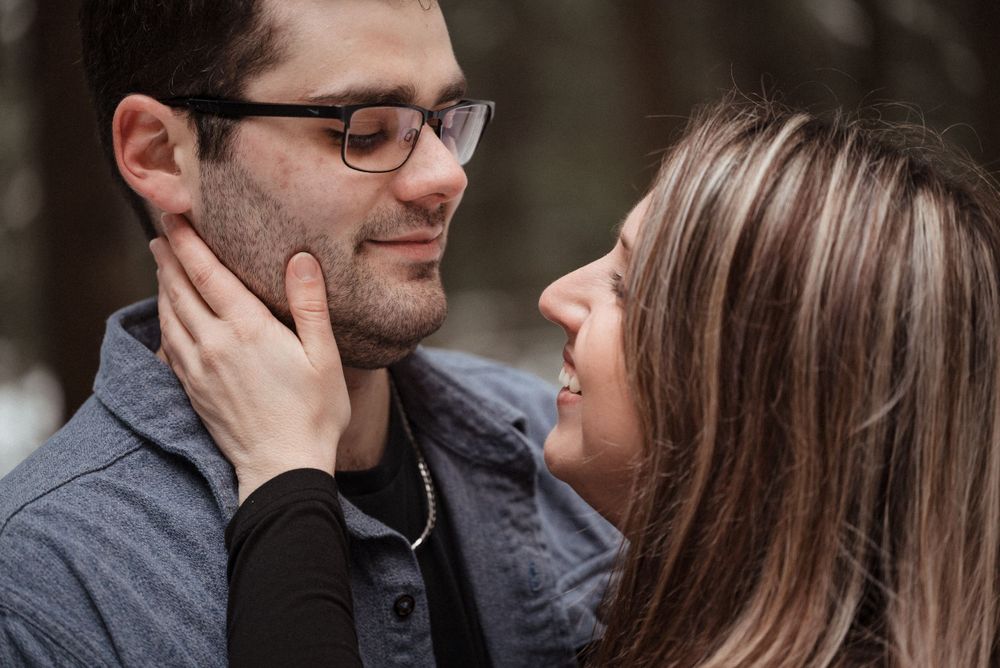 A tender romantic moment between a couple gazing at each other in a forest setting.