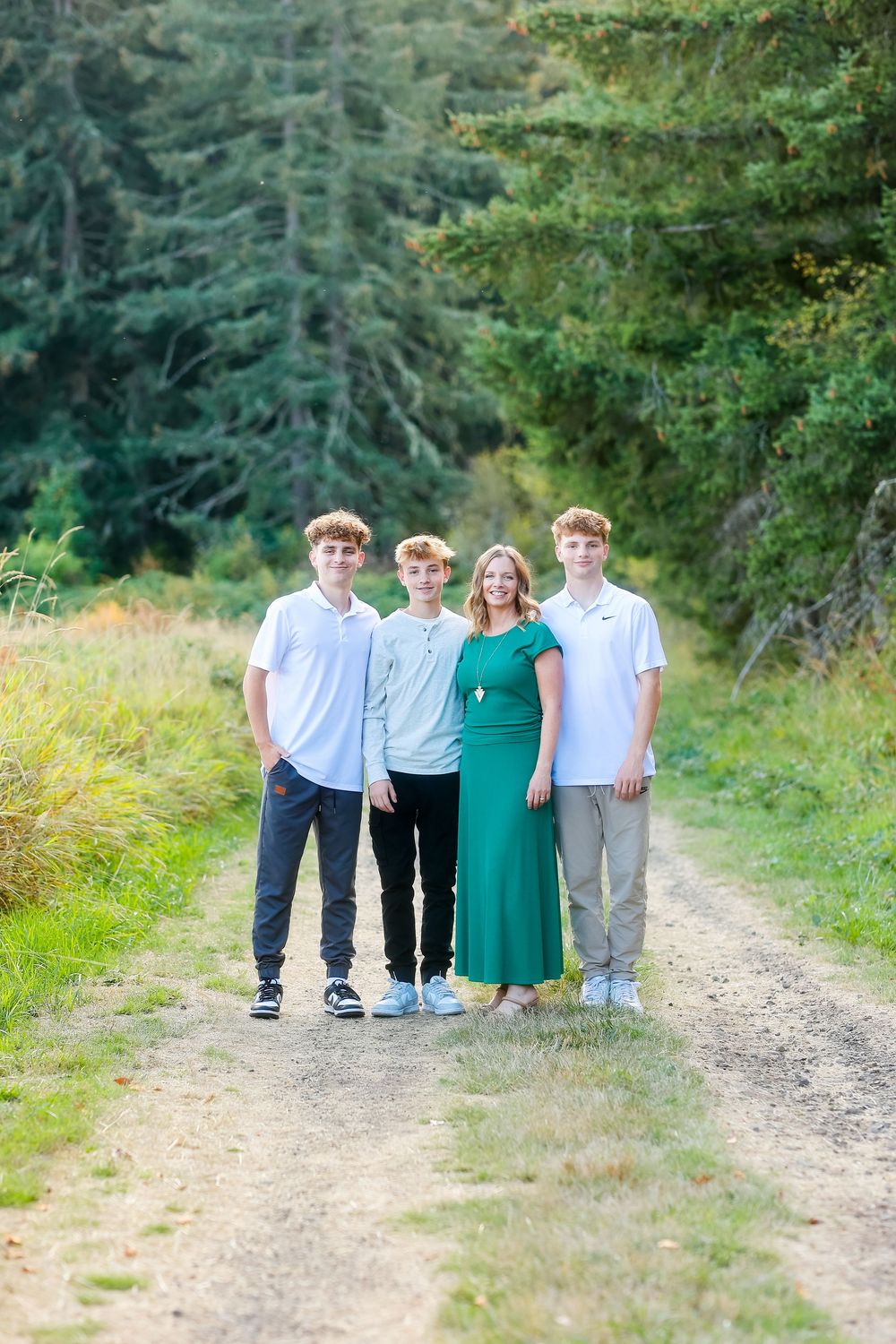 A group stands together on a dirt path surrounded by lush green trees and foliage on a sunny day.
