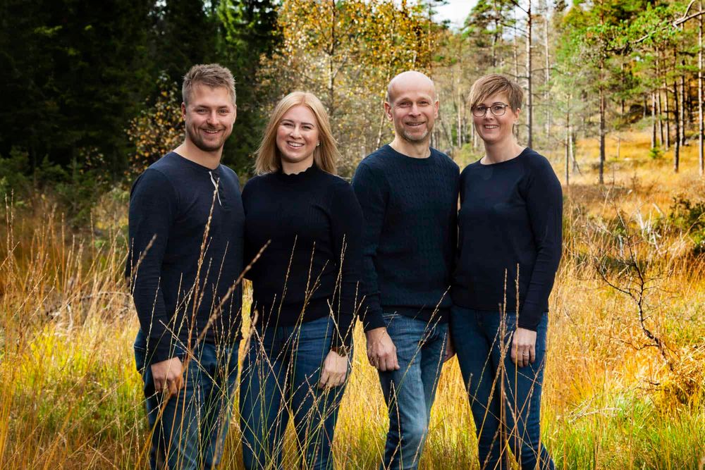 Familie på 4 voksne med like klær som smiler til fotografen på familiefotograferiing i skogen i Lyngdal
