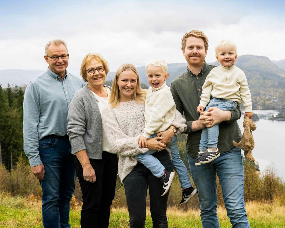 Storfamilie med 3 generasjoner hvorav 2 små gutter som alle ser i kamera og smiler på en høyde i Flekkefjord