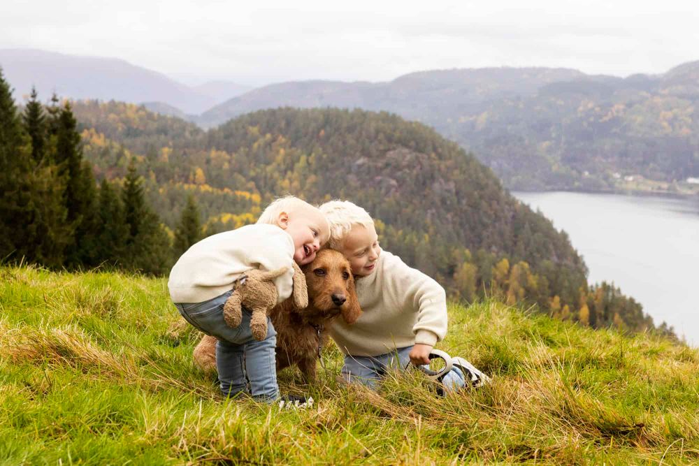 To små gutter som koser en hund på familiefotografering på en høyde i Flekkefjord