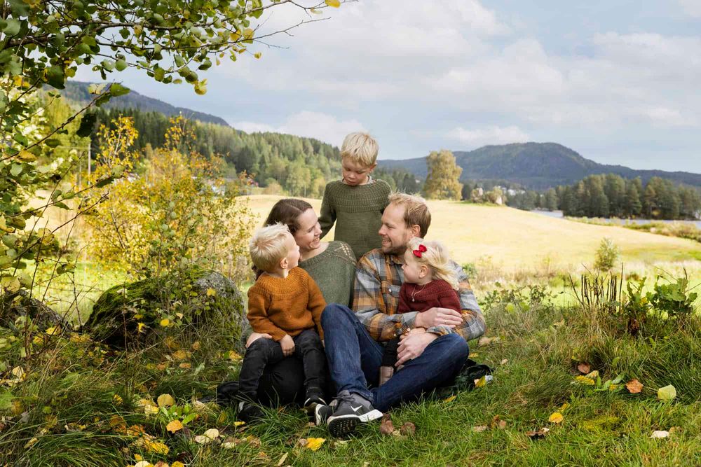 Familie på 5 som sitter i et skogbryn i Lyngdal og ser på hverandre og koser seg