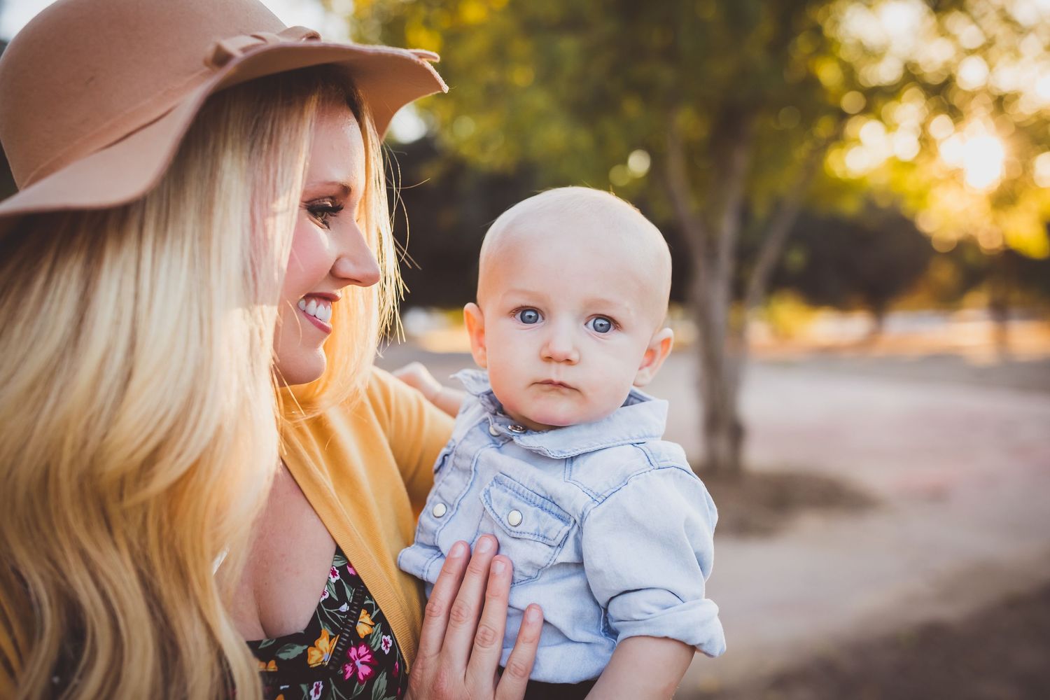 An adult and baby share tender moments outdoors at sunset, creating heartwarming family portraits in warm golden light.