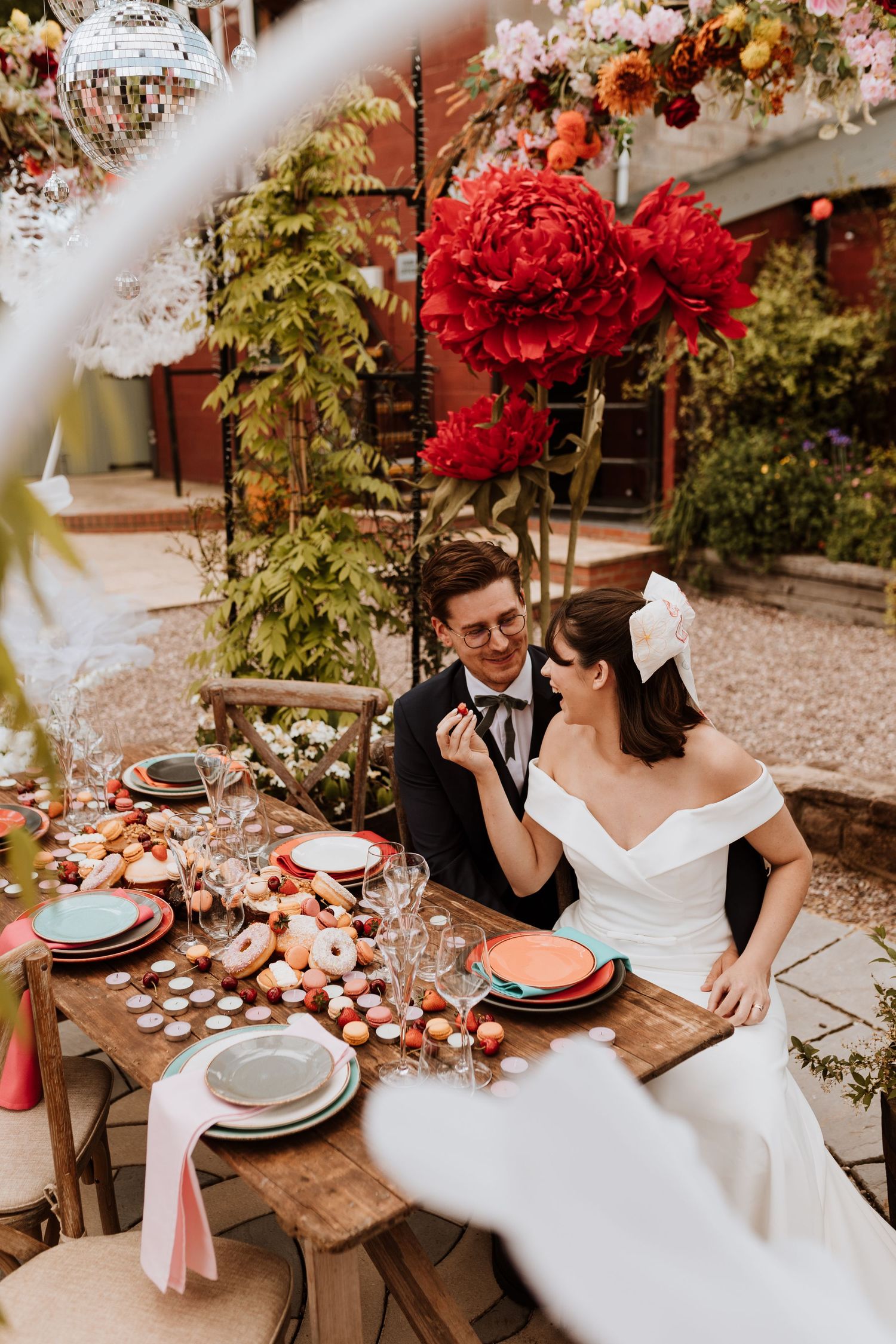 A romantic outdoor wedding reception table setup with red floral arrangements and rustic wooden decor at Stanford Farm.