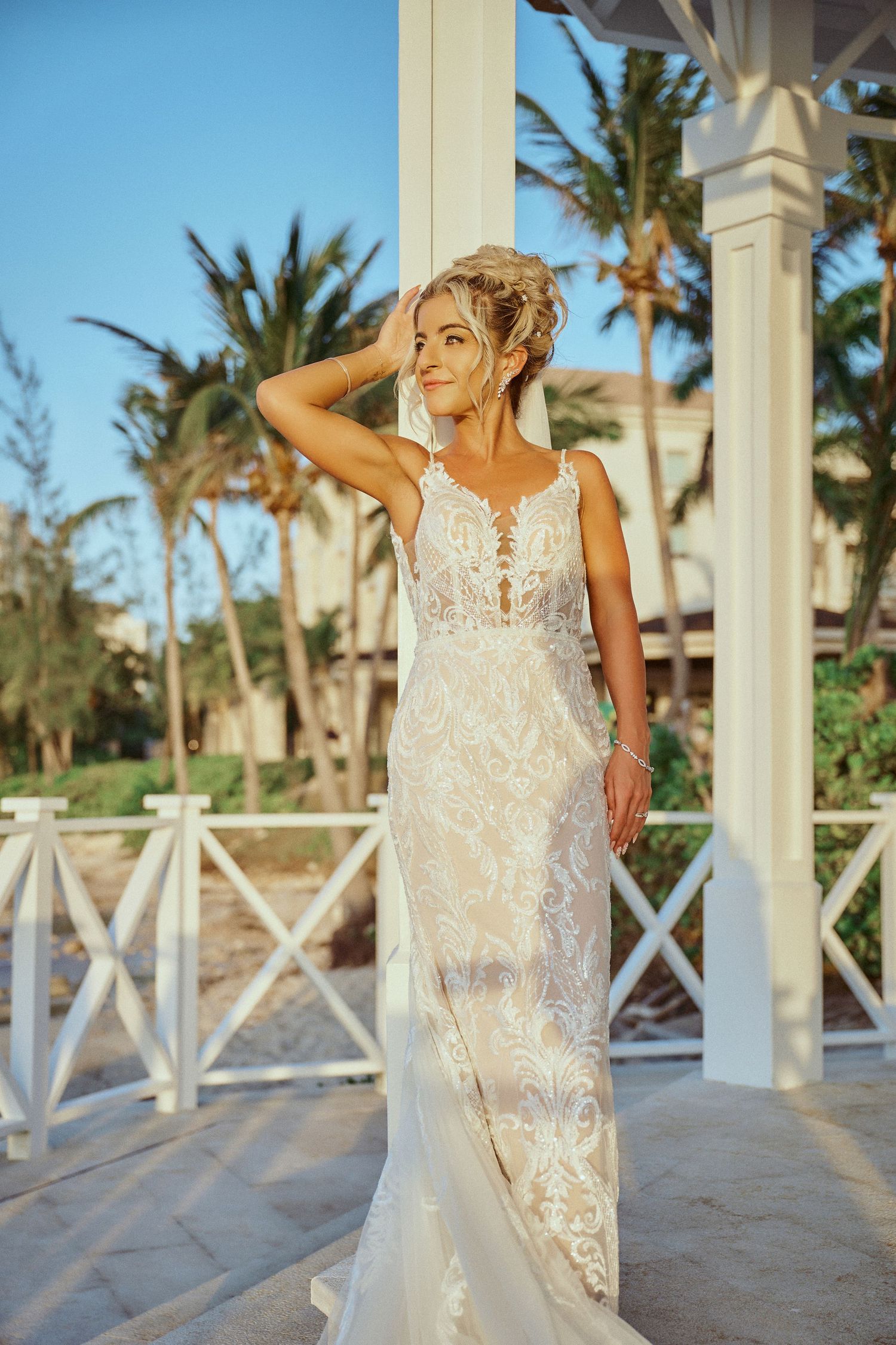 Elegant lace wedding dress with plunging neckline and fitted silhouette shown against tropical palm Jamaica Wedding Photographer