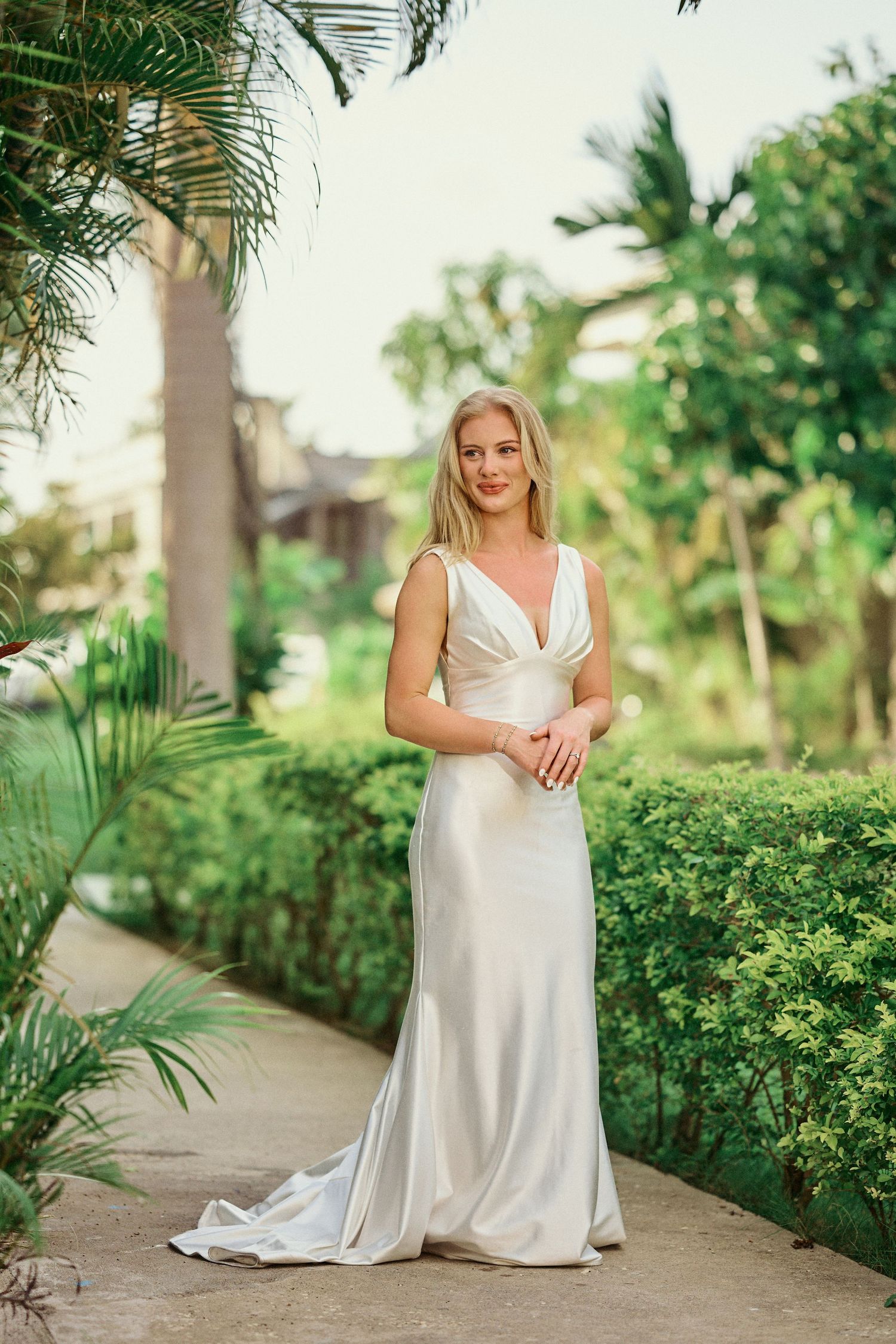 Elegant white silk wedding dress with v-neckline and fitted silhouette photographed on path with Jamaican Photographer