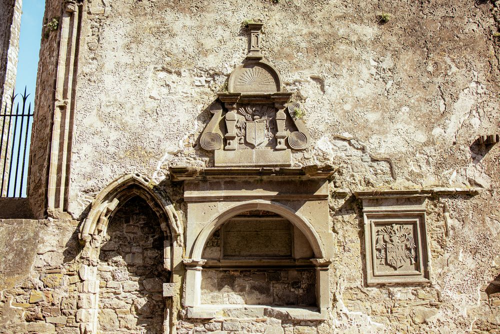 Ancient stone architectural detail with weathered arch and decorative carvings on medieval building wall.