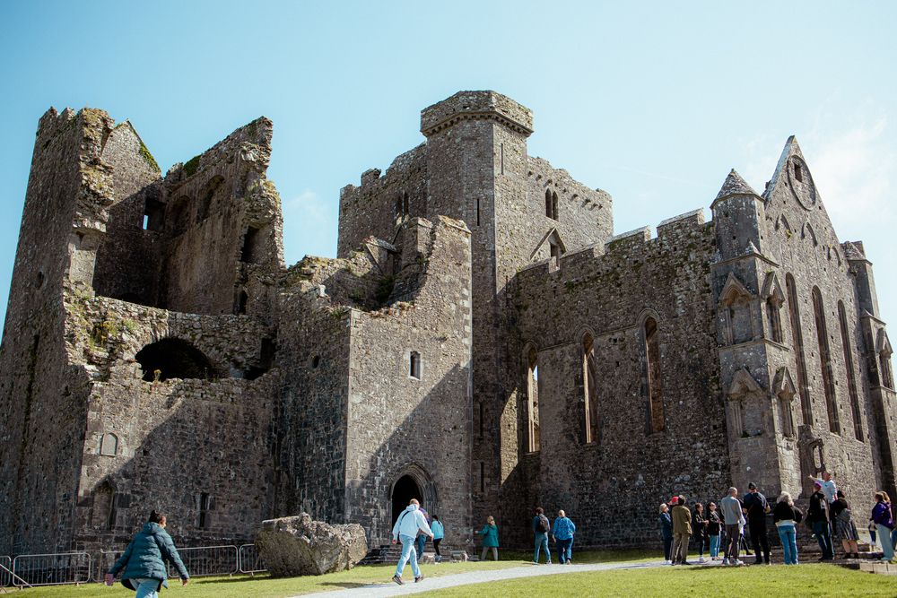Tourists explore the historic ruins of Rock of Cashel, an ancient medieval castle and cathedral complex in Ireland.