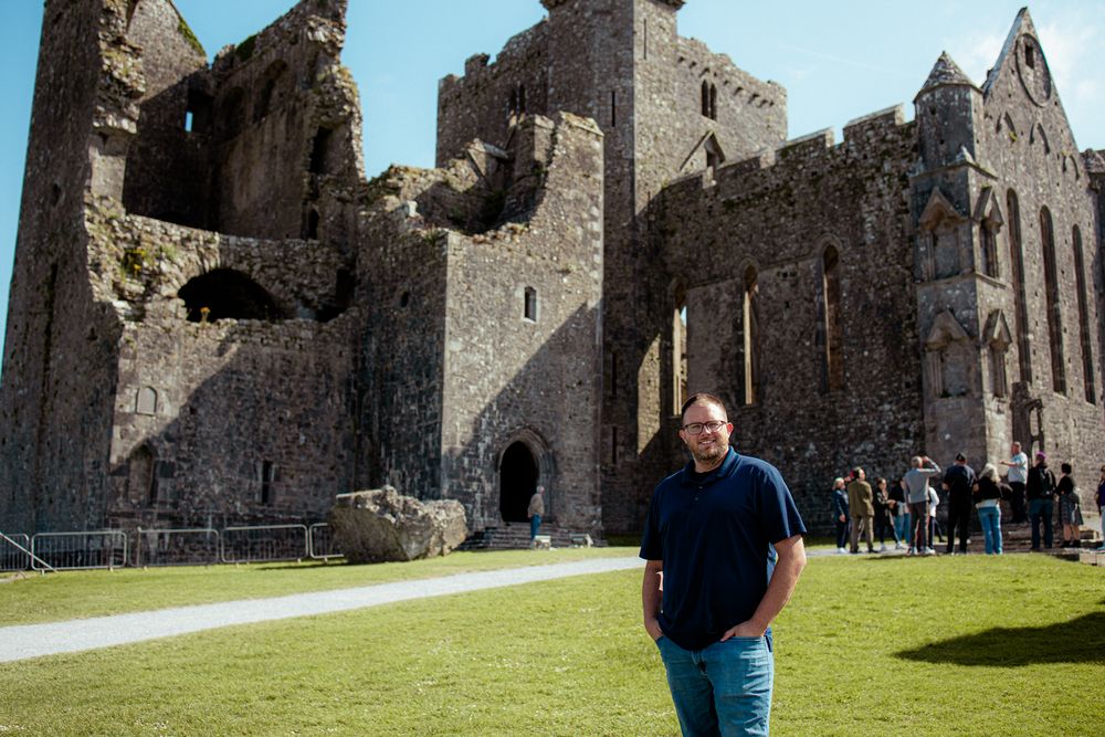 Historic ruins of the Rock of Cashel medieval castle and cathedral complex in Ireland with manicured lawn in foreground.