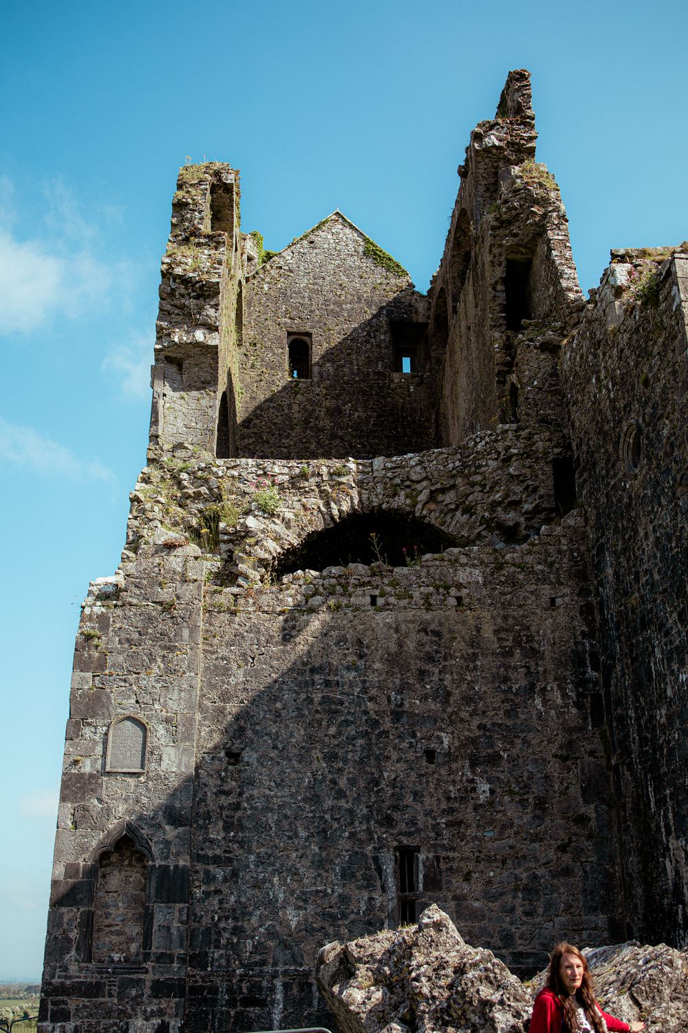 Ancient stone ruins of a medieval castle or fortress with tall crumbling walls against a bright blue sky.