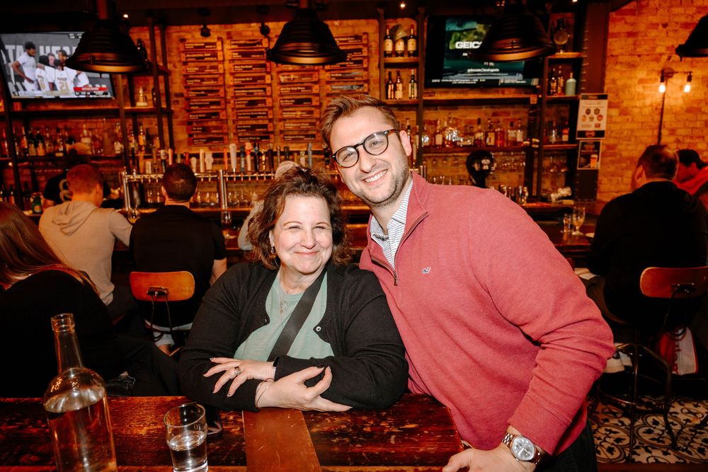 Two people enjoying drinks at a cozy bar with exposed brick walls and warm lighting.