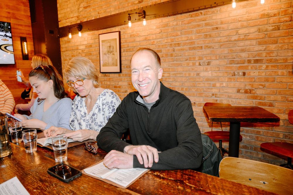 People sitting at a wooden table in a restaurant with exposed brick walls and warm lighting.