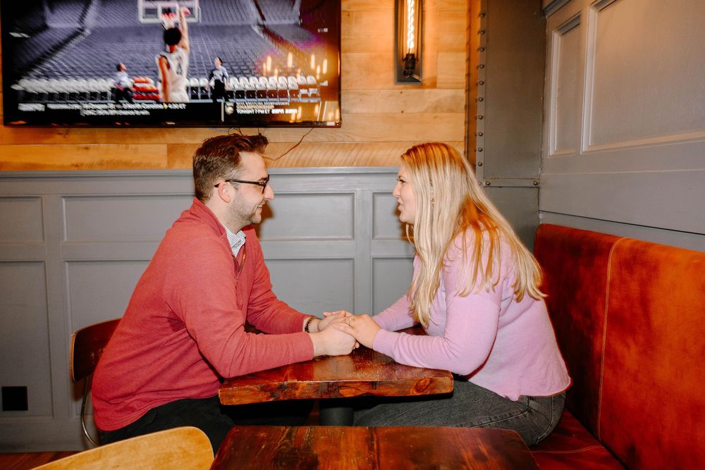 A couple sits at a table inside a restaurant having an intimate conversation.