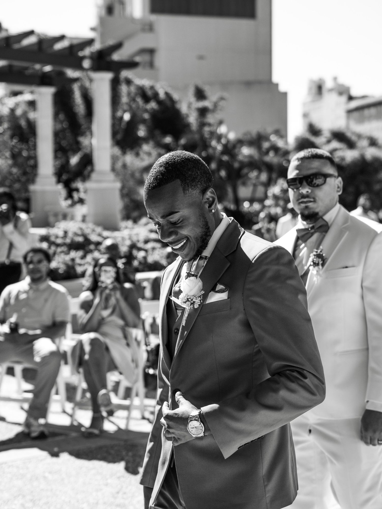 Black and white photo of wedding ceremony taking place in garden setting.